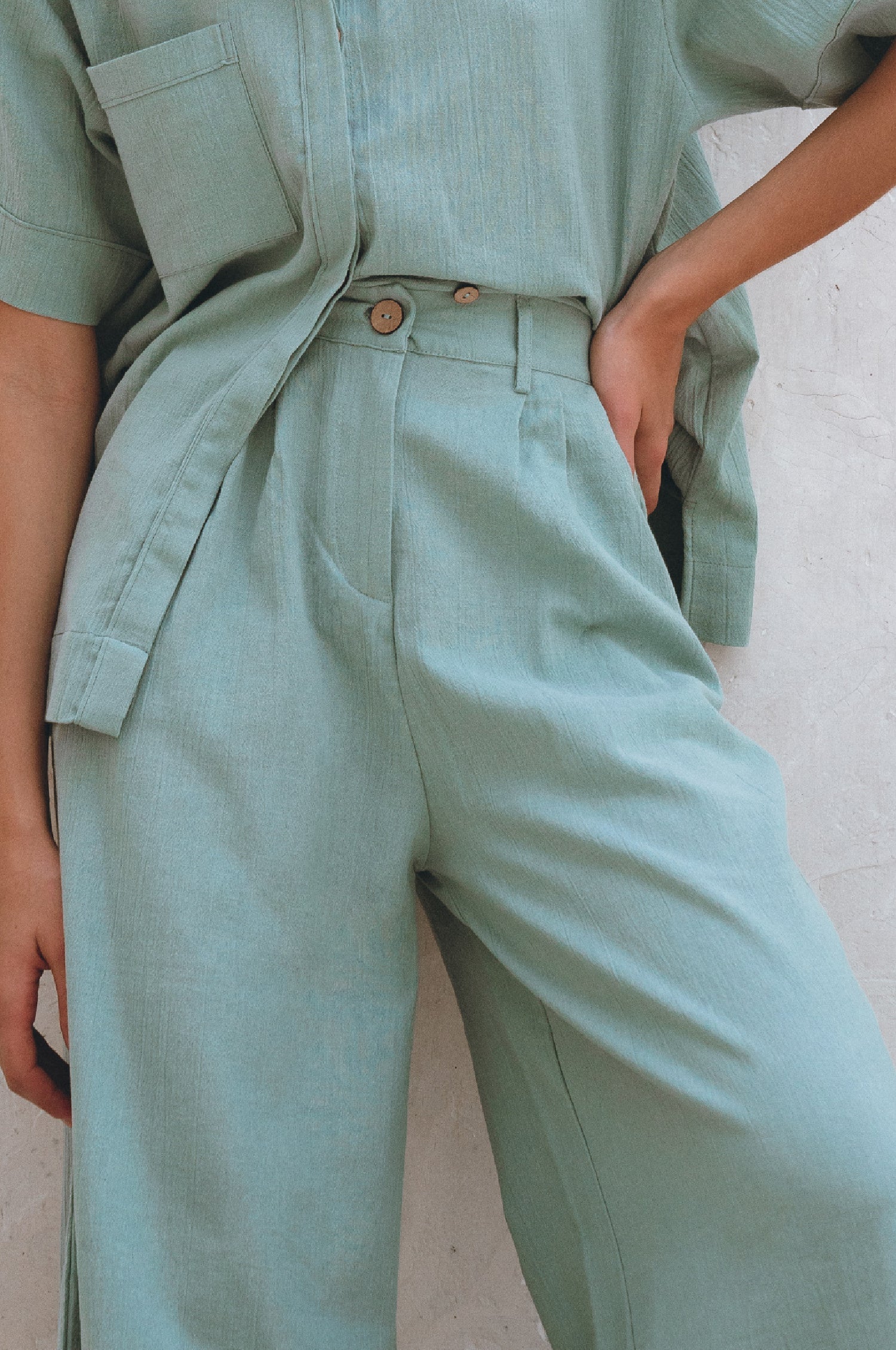 Person wearing a Classic Linen Pants in sage green showing waistband on a neutral background