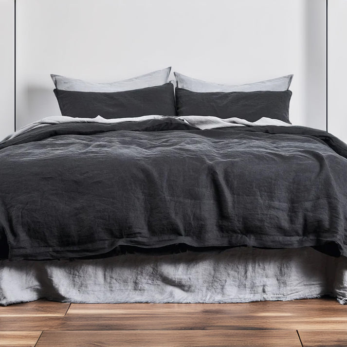 Charcoal black linen-cotton-duvet-set on a bed with a wooden floor and white wall background