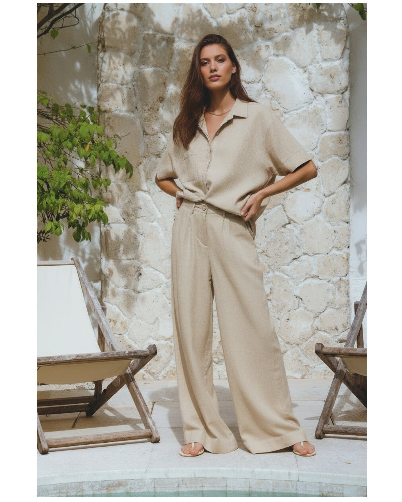 Classic linen pants in beige on model standing against a stone wall.