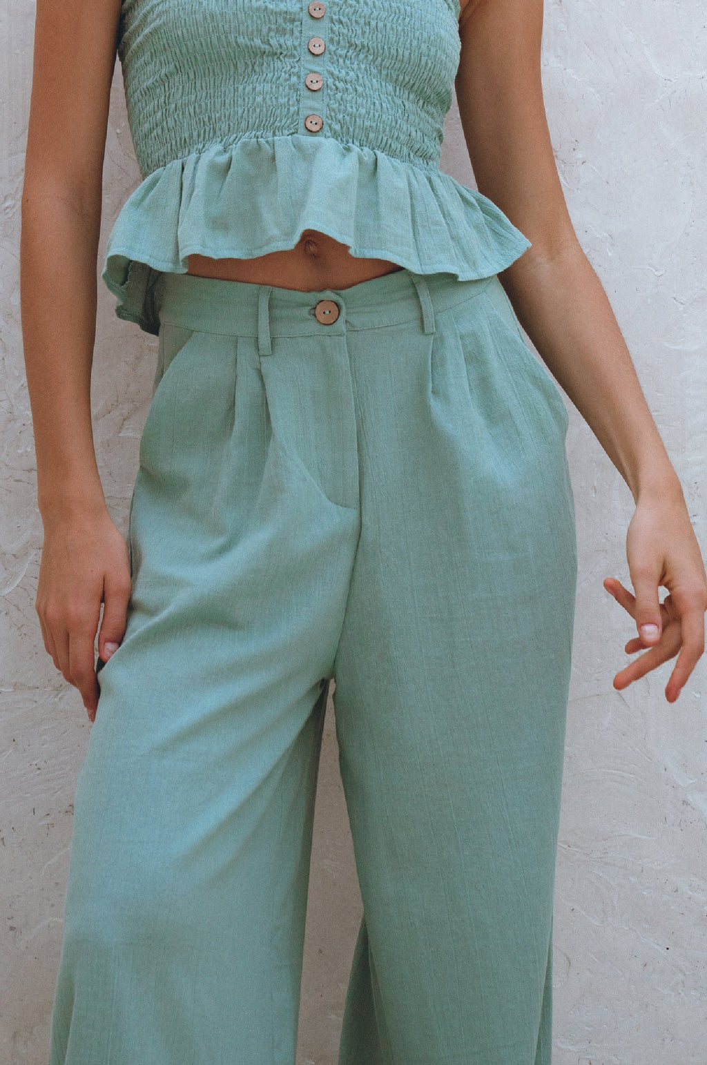 Person wearing a matching Sage green top and classic linenpants against a neutral background