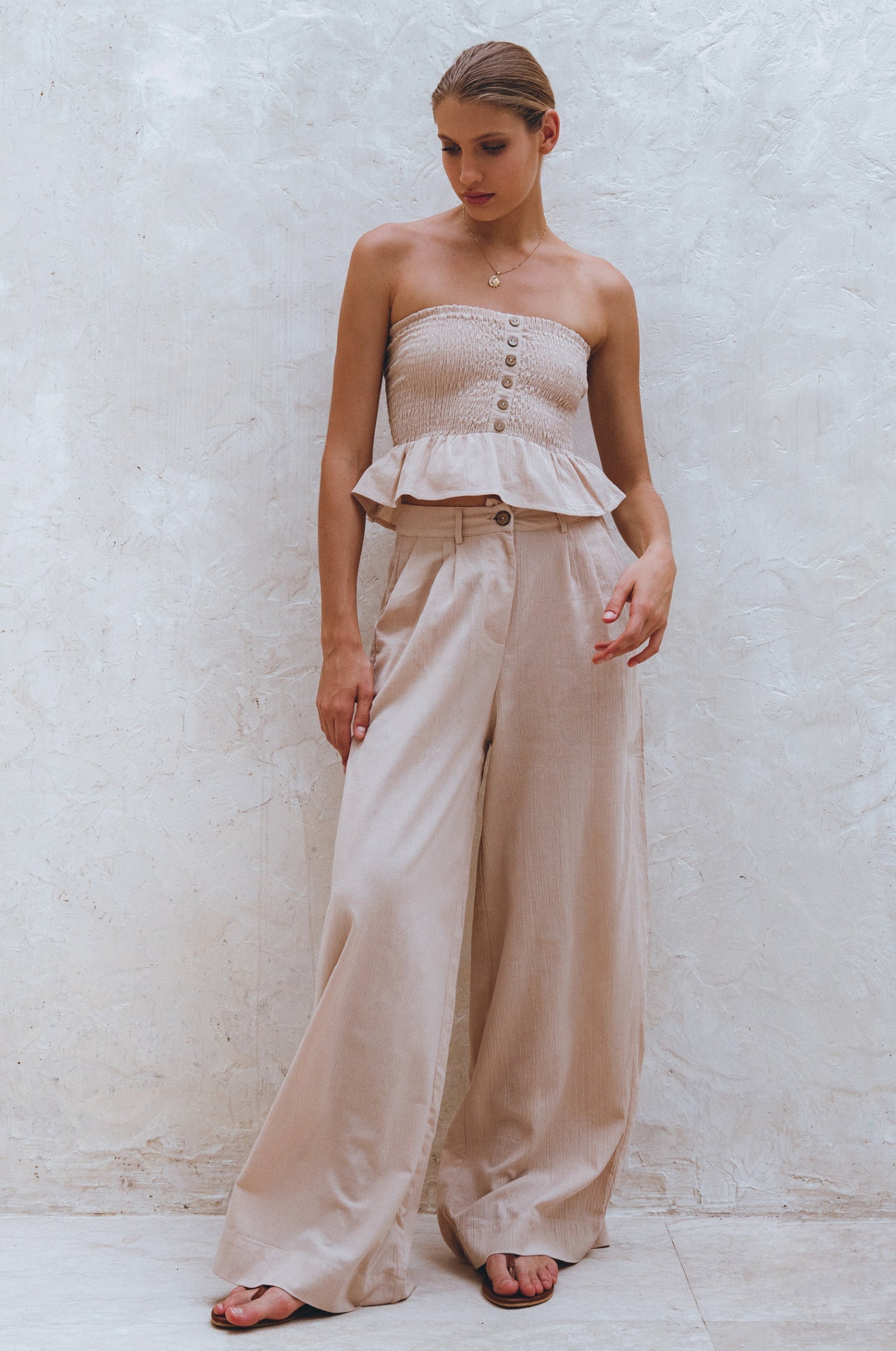Woman wearing a beige strapless top with a peplum and Beige Classic Linen Wide -leg Pants against a white background