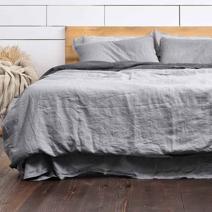 Gray linen cotton duvet set on a bed with a wooden headboard against a white paneled wall.