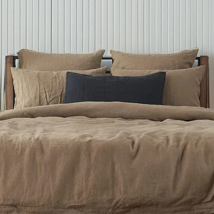 Dusty brown linen and cotton duvet and shams on a wooden bed against a white paneled wall.