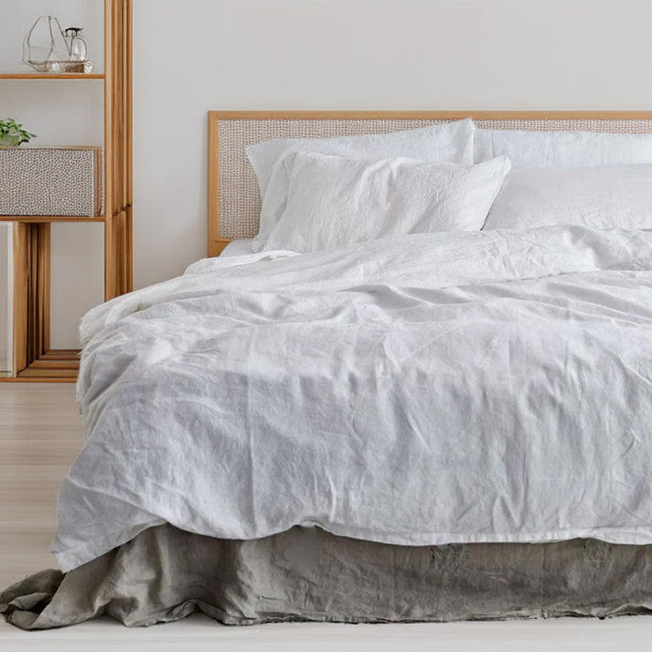 Linen cotton duvet cover and shams white bedding set on a bed with a wooden headboard in a bedroom setting.