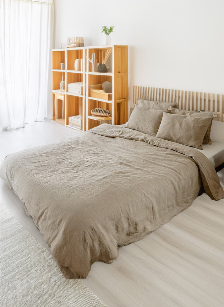 Linen and cotton beige duvet cover and shams on a bed in a room with wooden shelves and white walls