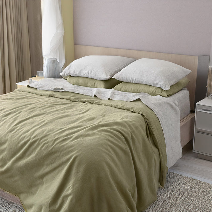 Bed with pistachio green linen and cotton duvet set in a bedroom setting