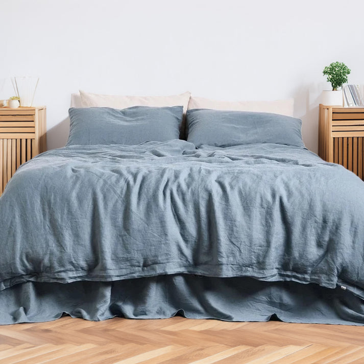 Teal blue linen and cotton duvet set on a bed in a bedroom with wooden floors and furniture.